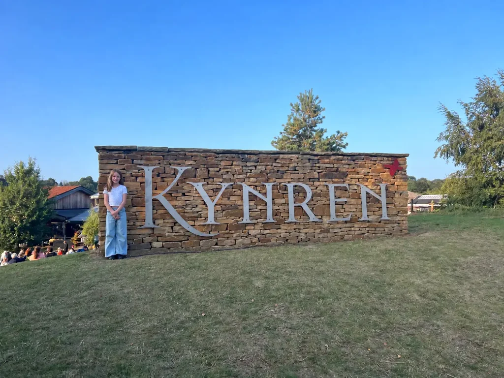 Home Child standing beside the Kynren sign before the show